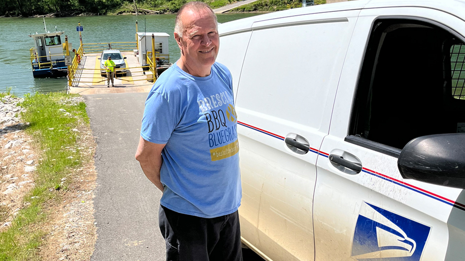 Larry Wilson, a Tompkinsville, KY, rural carrier, stands near the ferry he uses to help make his deliveries.