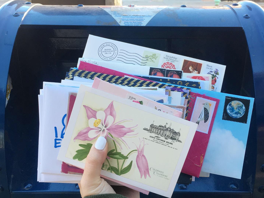 A woman's hand holds a bundled of stamped envelopes containing hand-written letters