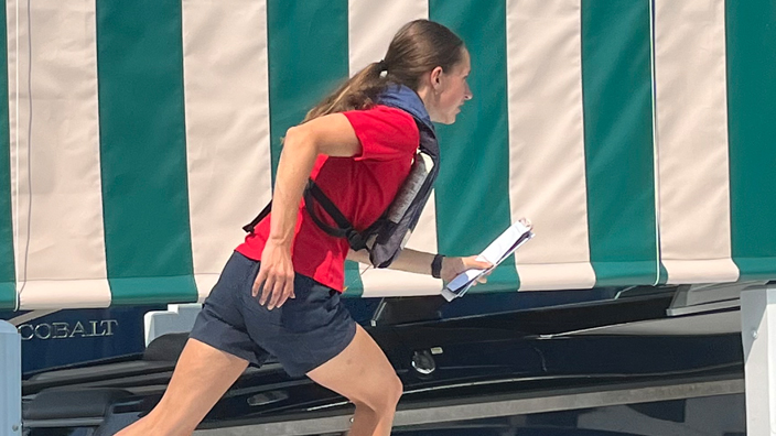 A woman runs along a boat pier while carrying mail.