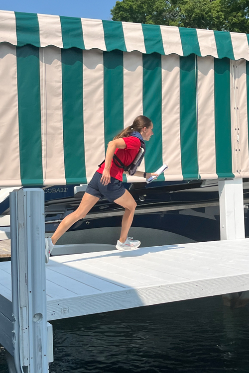 A woman runs along a boat pier while carrying mail.