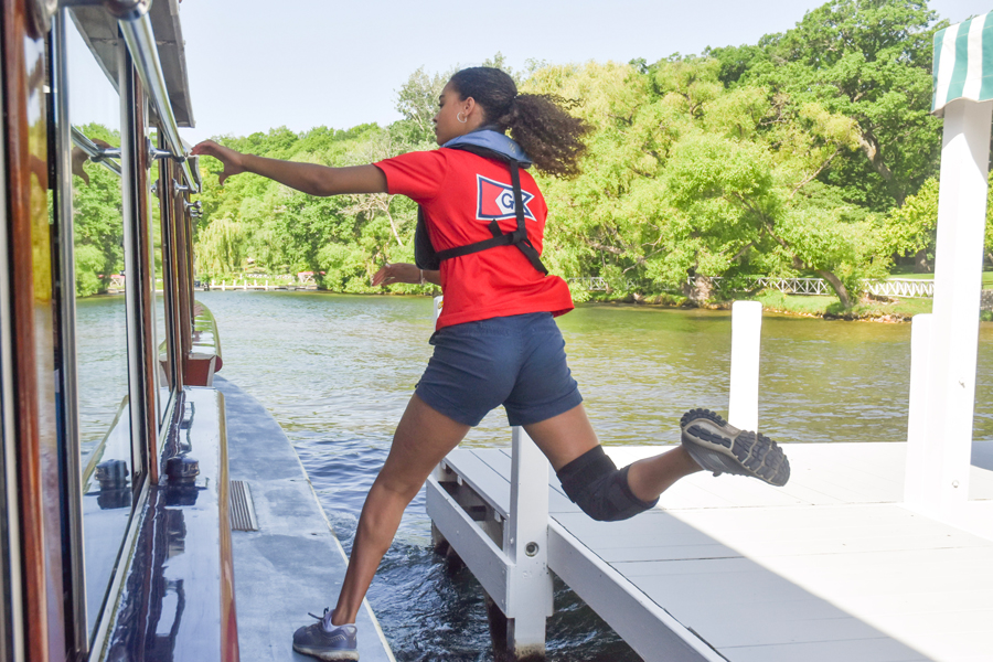 A woman jumps onto a boat from a dock.