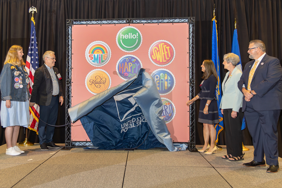 Jennifer Miller, American Topical Association executive director; Greg Breeding, USPS art director; Shibani Gambhir, USPS sales intelligence and support vice president; Dawn Hamman, American Topical Association president; and Scott English, American Philatelic Society executive director, dedicate the Postal Service’s Pinback Buttons stamps.