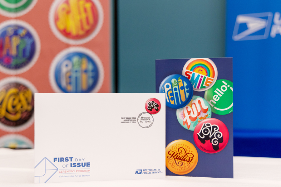 A souvenir envelope and program are displayed at the Pinback Buttons stamp dedication ceremony.