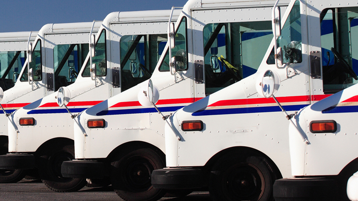 USPS-branded delivery vehicles parked in a row