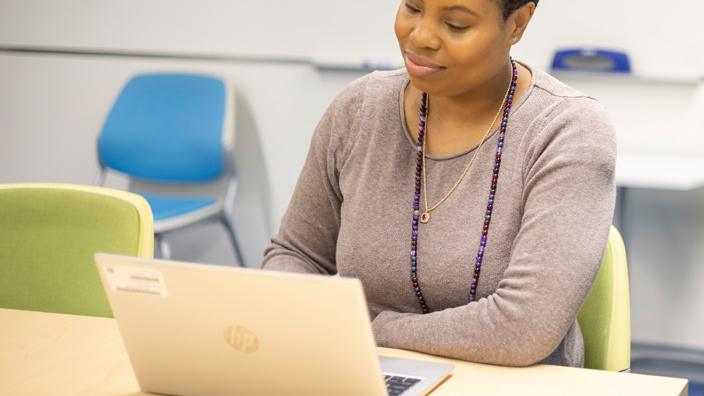 Smiling woman sits at laptop