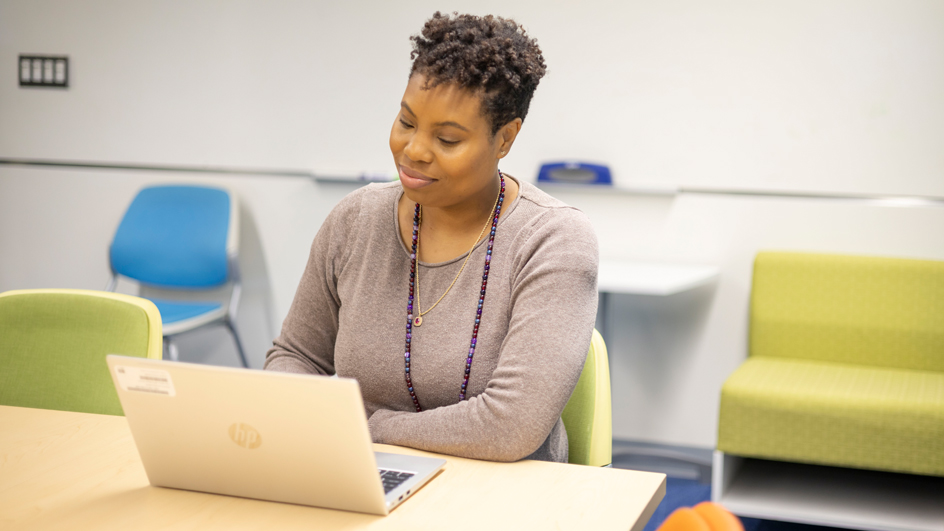 Smiling woman sits at laptop