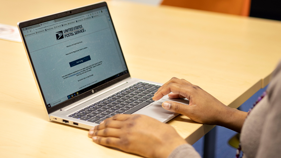 A postal employee uses a laptop computer to complete the Postal Pulse survey