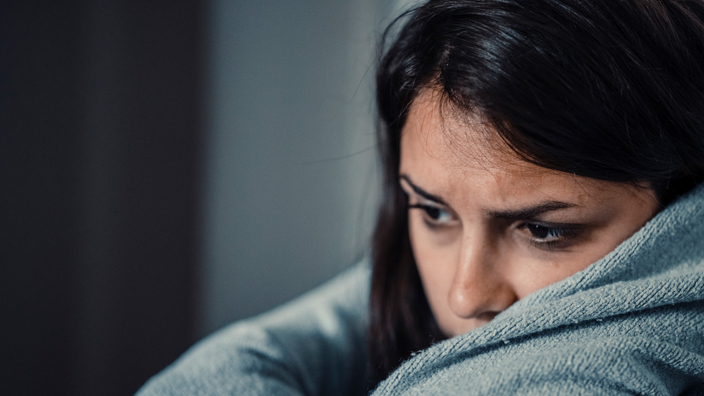 A sad-looking woman wearing a gray sweater