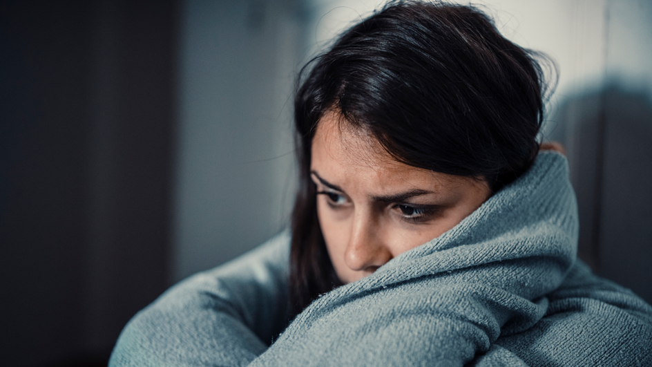 A sad-looking woman wearing a gray sweater