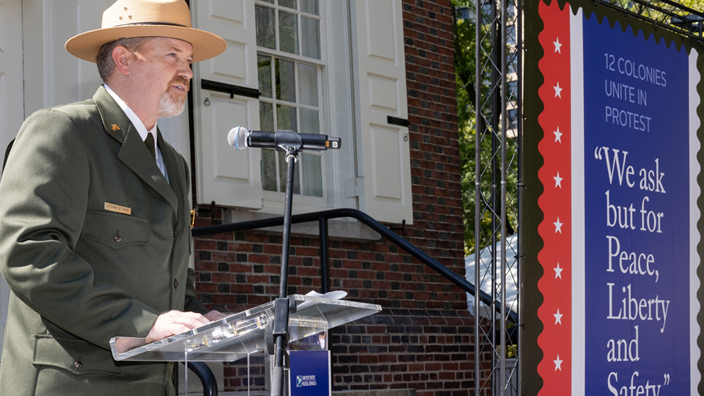 A man in a uniform speaks from behind a small lectern