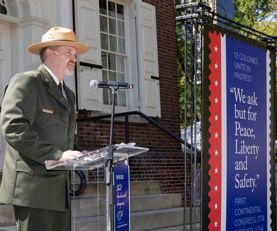 A man in a uniform speaks from behind a small lectern