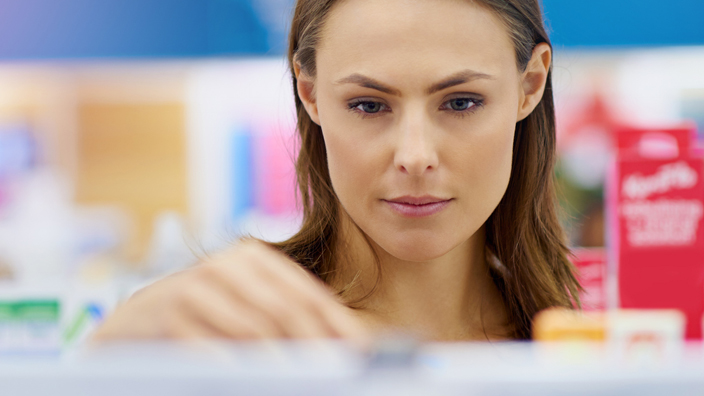 A customer looks at products on a pharmacy shelf