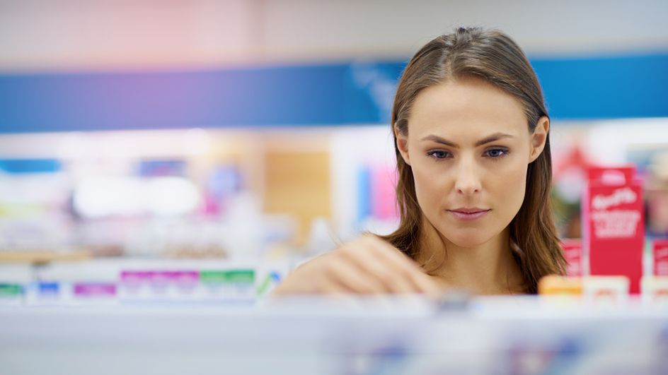 A customer looks at products on a pharmacy shelf