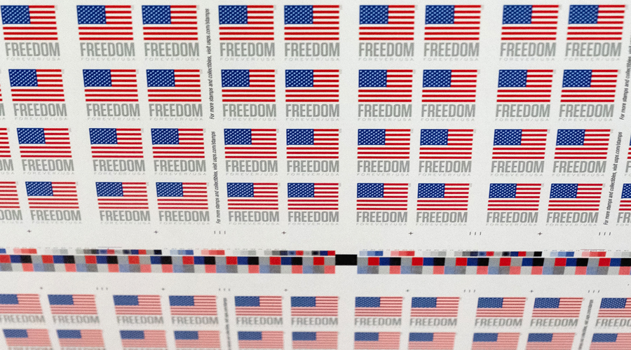 A sheet of stamps rolling off a printing press.