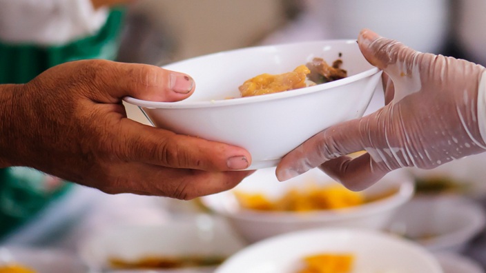 A volunteer handing out a bowl of food