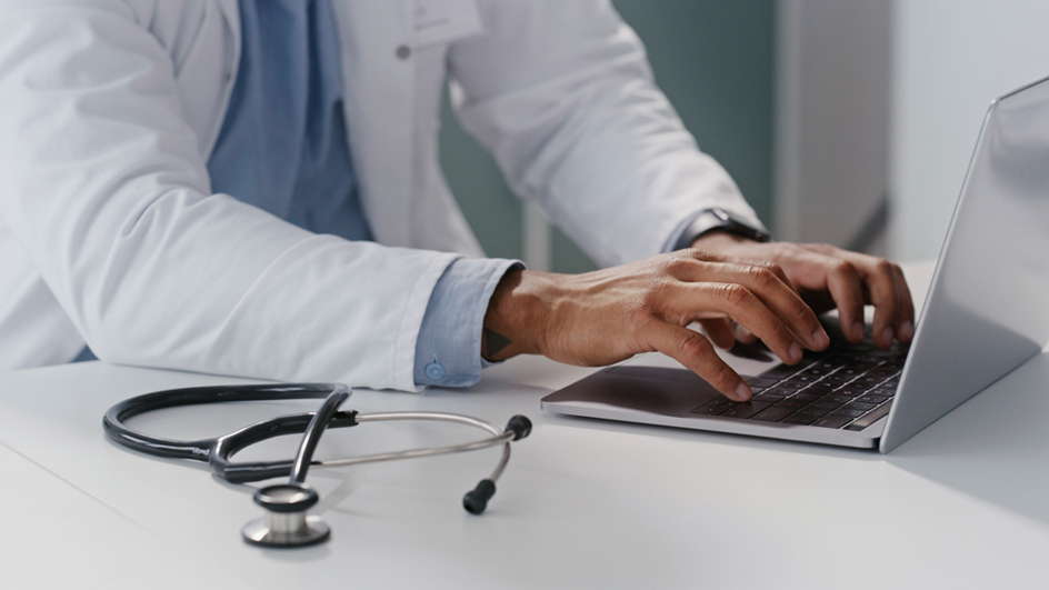 A medical professional typing on a laptop computer