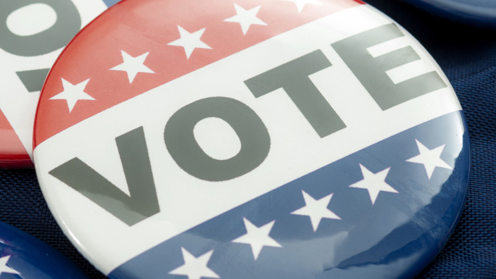 A display of buttons with patriotic colors that read "Vote"