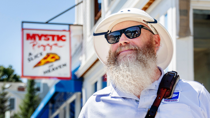 Letter Carrier Brett Swanson stands on a street in Mystic, CT.