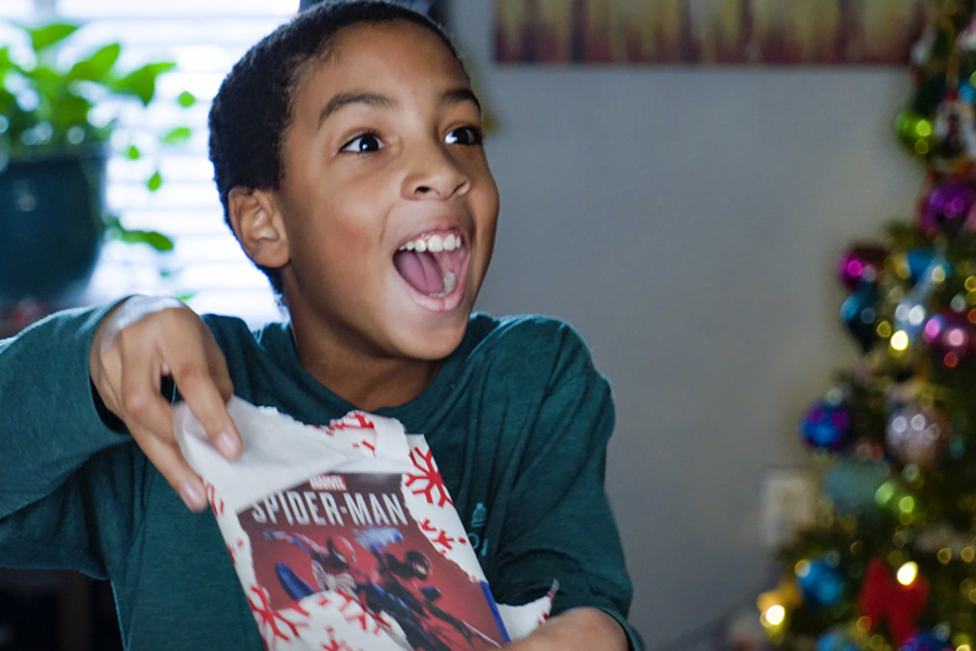 A child opens a Chrirsmas gift from the USPS Operation Santa program