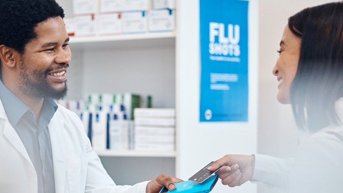 A pharmacist smiles at a customer using a FSA debit card