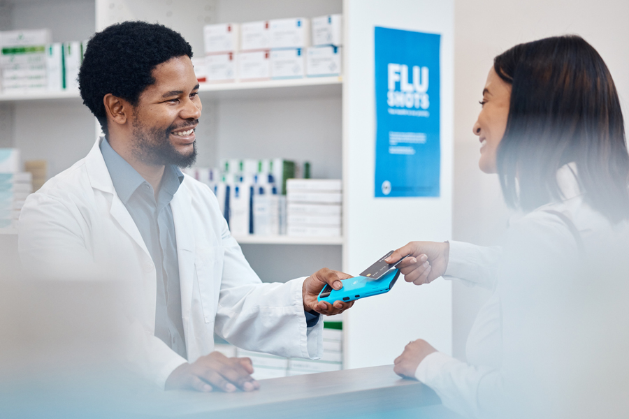 A pharmacist smiles at a customer using a FSA debit card