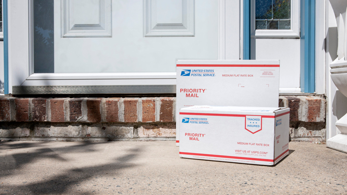 Two USPS Priority Mail packages sitting on a doorstep.