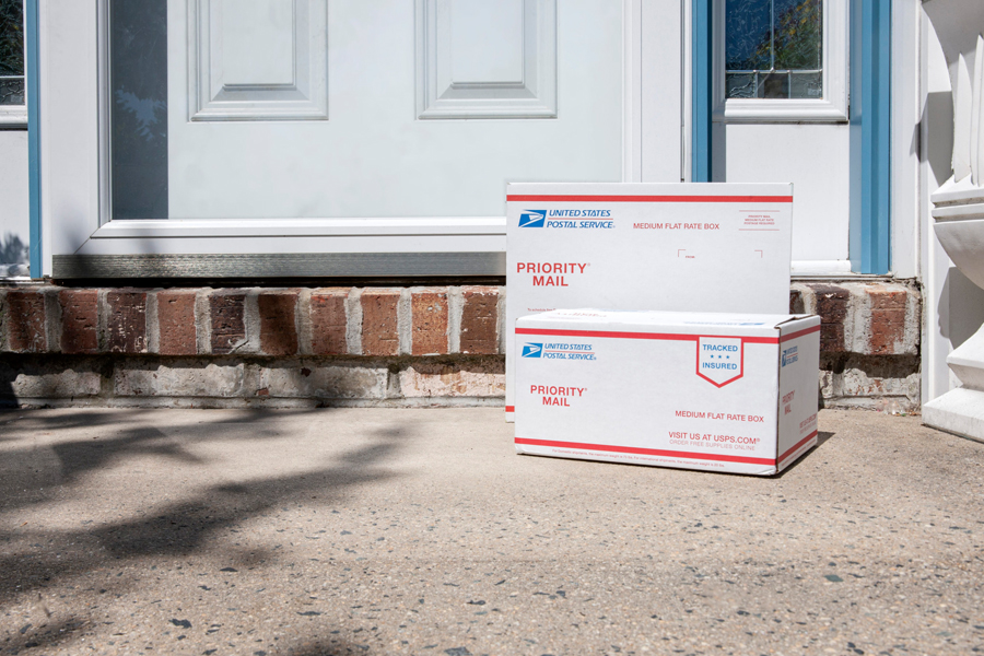 Two USPS Priority Mail packages sitting on a doorstep.