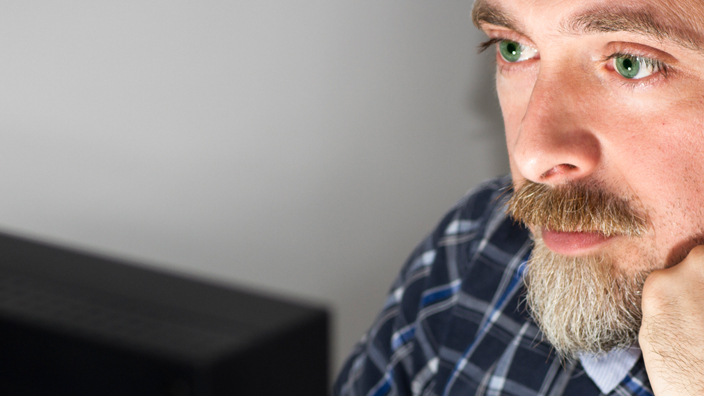 A man peering at a computer screen