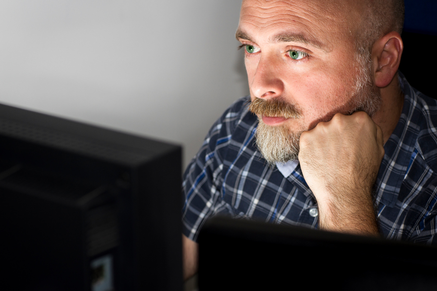 A man peering at a computer screen