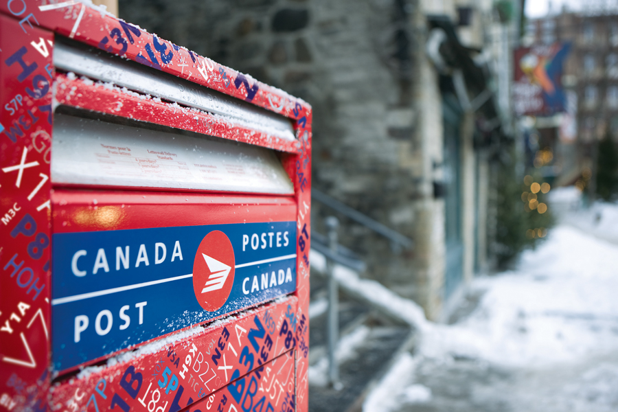 A red Canada Post mail box along a street.