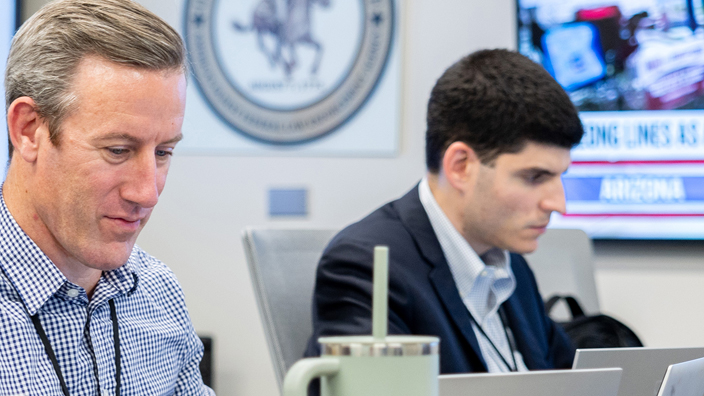 Two U.S. Postal Inspection Service employees using laptop computers.