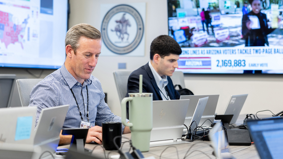 Two U.S. Postal Inspection Service employees using laptop computers.