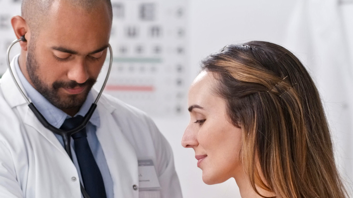 A doctor listening to a patient's heartbeat