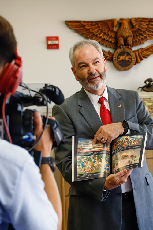 Stephen Kochersperger, the USPS historian, displays a book of postal murals during the taping of a “Real Virginia” TV segment.