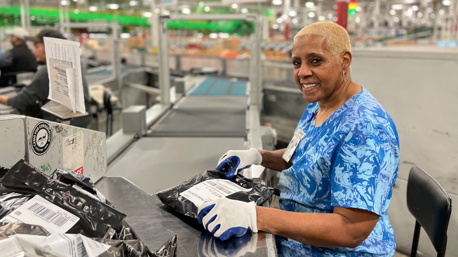 Tonya Ferguson, a Columbus, OH, mail processing clerk, uses a package sorting machine.