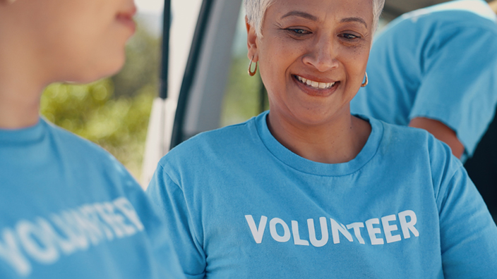 Three volunteers in turquoise T-shirts marked "volunteer" at an event