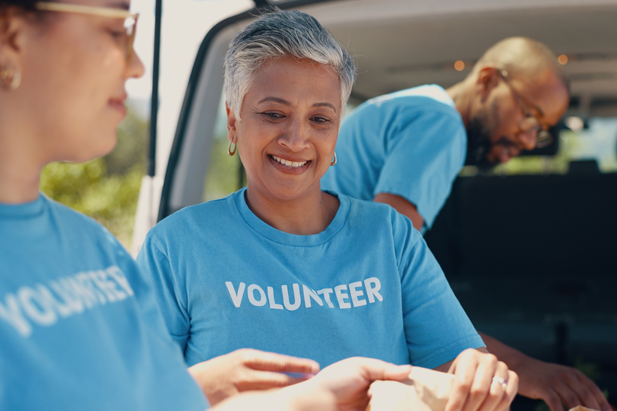 Three volunteers in turquoise T-shirts marked "volunteer" at an event