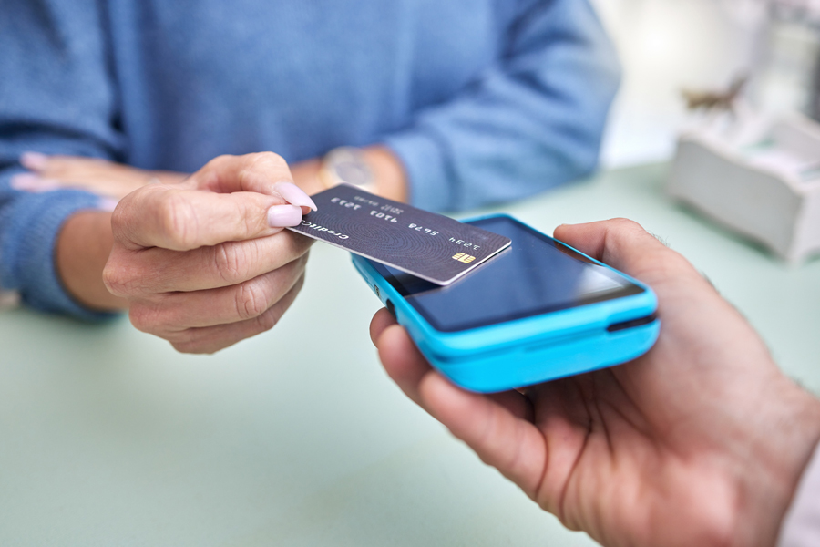 A woman taps a credit card on a handheld scanner.