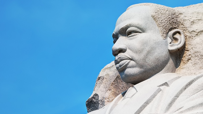 A close-up of a statue of Martin Luther King Jr. emerging from a mountainside