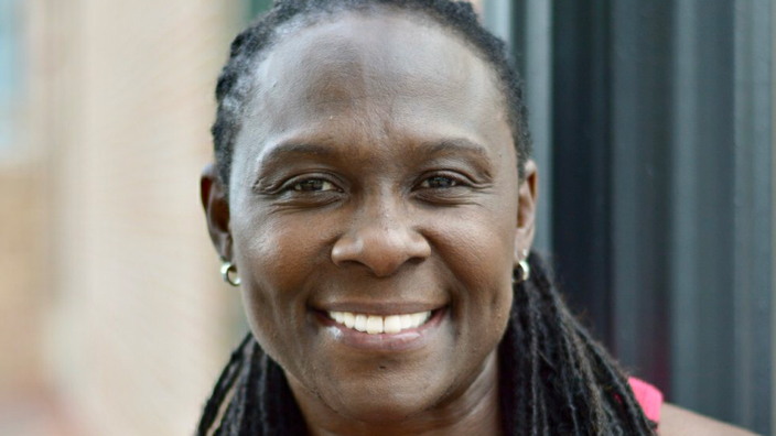 A woman wearing a pink tank top smiles brightly