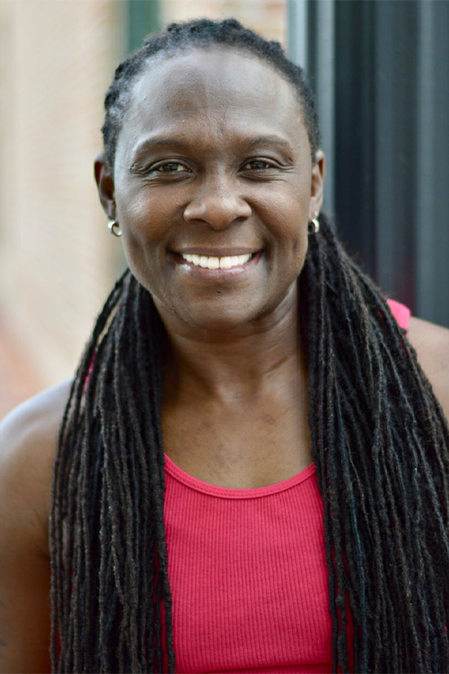 A woman wearing a pink tank top smiles brightly