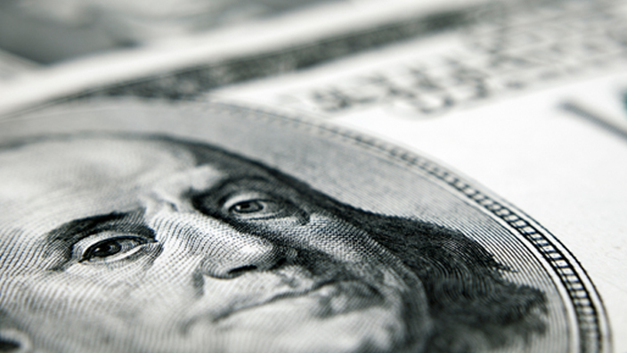 A close-up of a one hundred dollar bill in U.S. currency, with Benjamin Franklin’s portrait shown