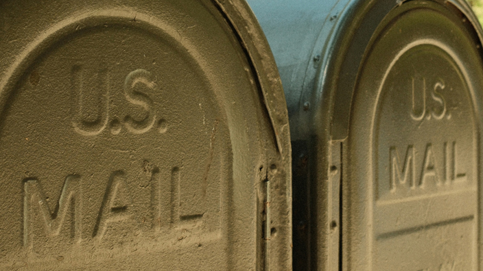 Two green Postal Service relay boxes located on an urban sidewalk