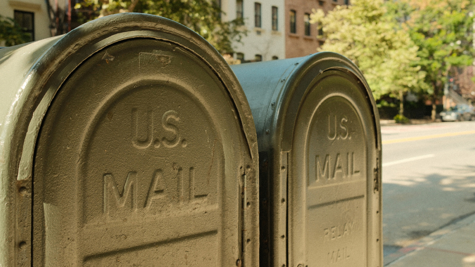 Two green Postal Service relay boxes located on an urban sidewalk