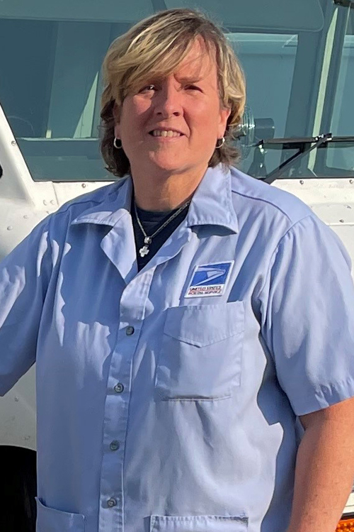 A woman stands next to a USPS delivery truck