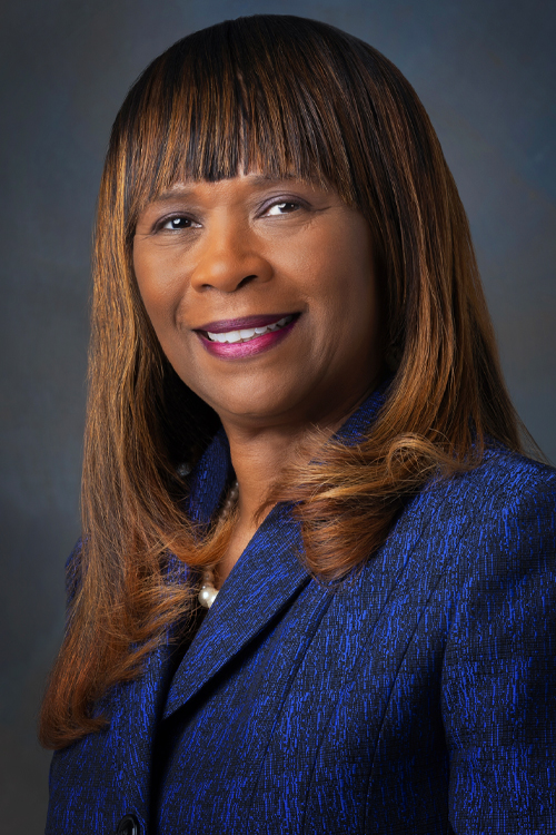 A studio portrait of a smiling woman dressed in business wear