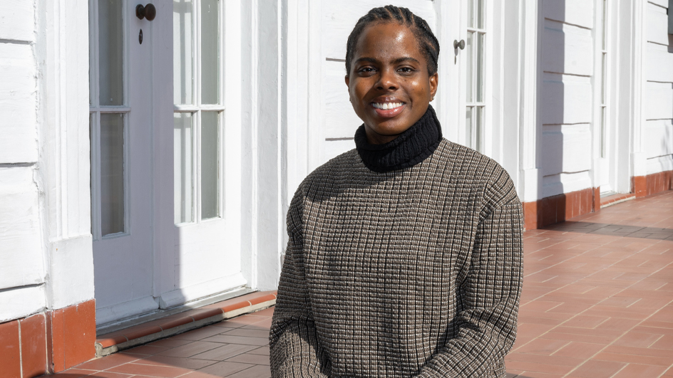 A woman smiles brightly while sitting on a stoop outside a building