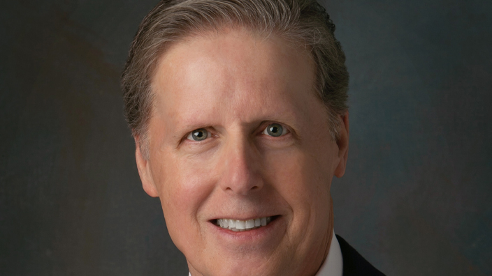 A studio portrait of a smiling man in a business suit and tie