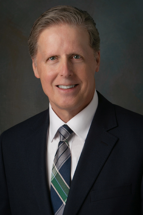 A studio portrait of a smiling man in a business suit and tie