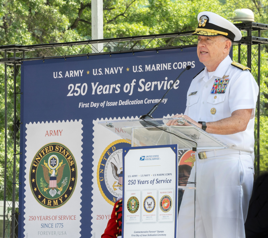 A man in a Navy uniform speaks at a lectern